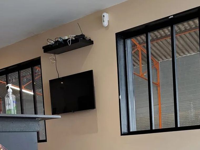 La verrière de l'accueil ouvrant sur l'atelier, où l'on distingue la charpente métallique orange.